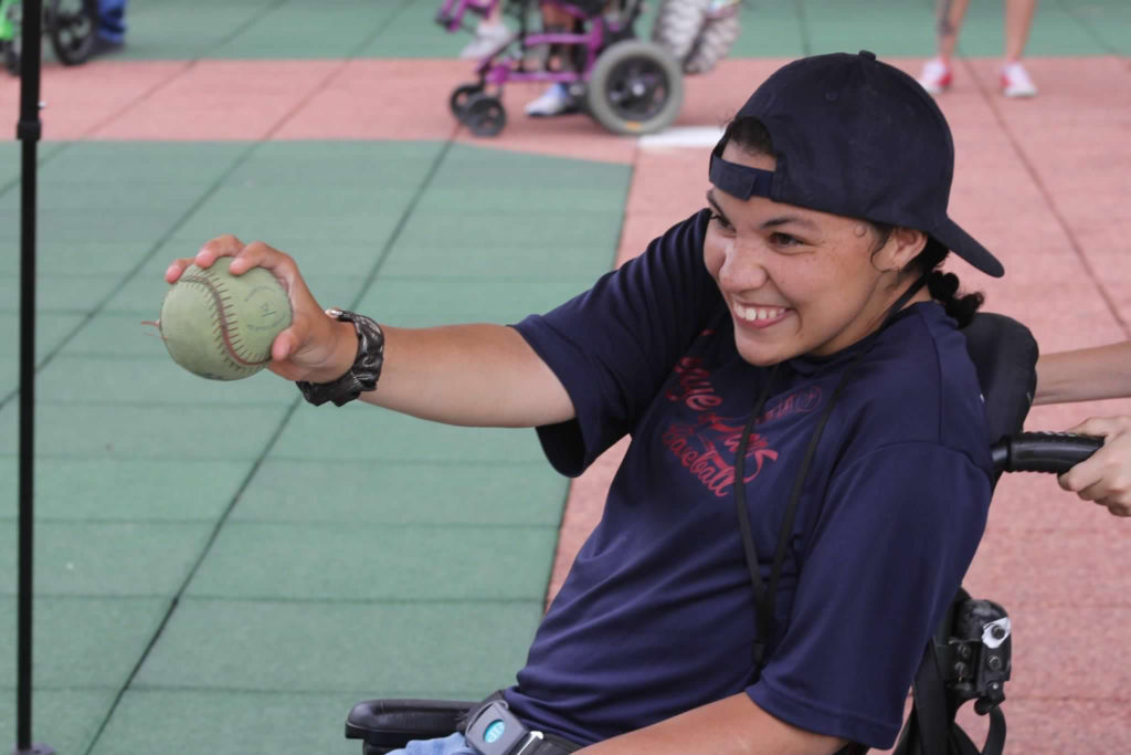 female athlete in a wheelchair smiling while holding a baseball