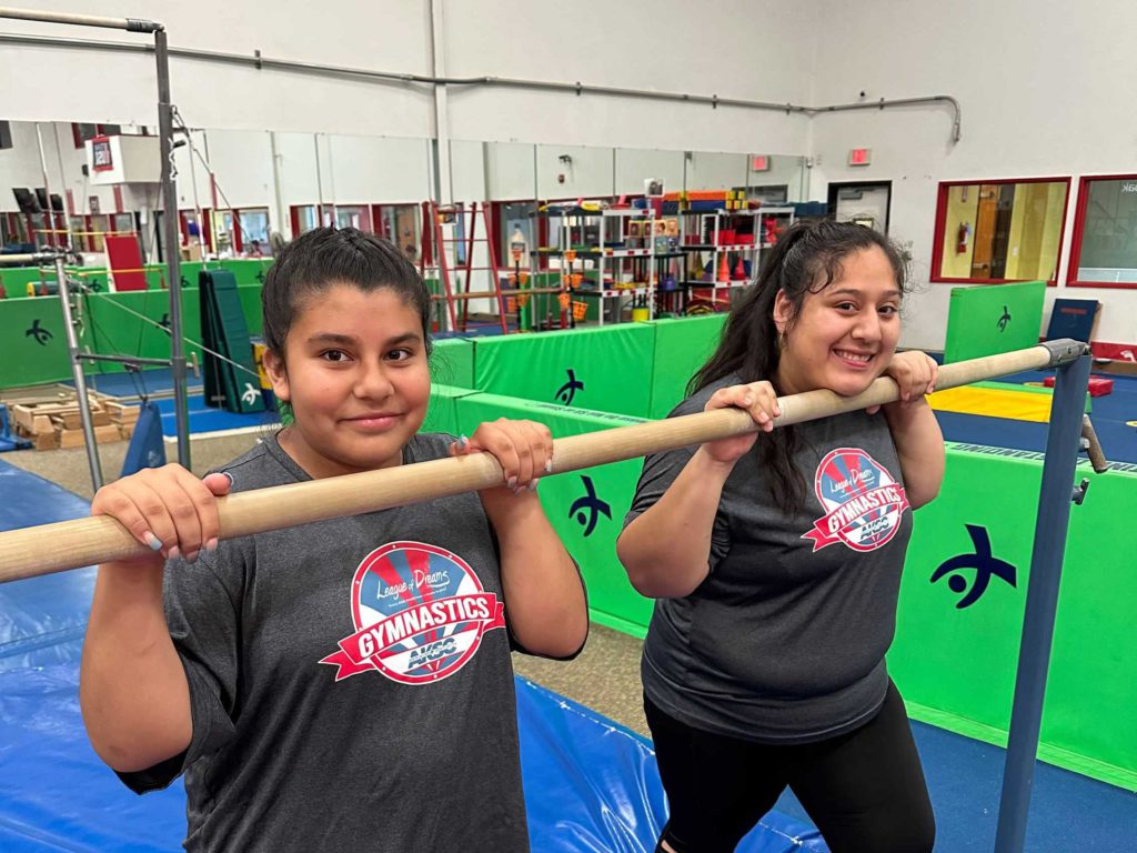 two female athletes holding onto a gymnastics bar
